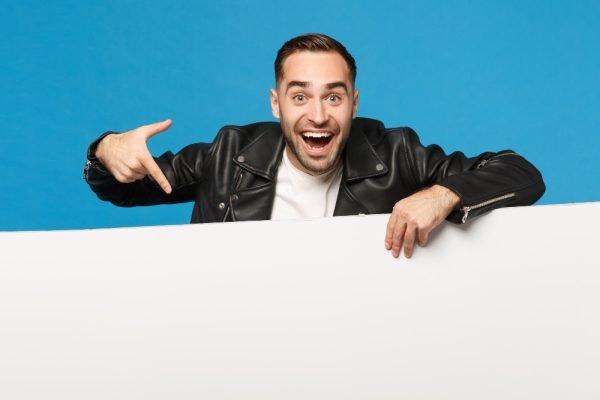 handsome-young-unshaven-man-hold-big-white-empty-blank-billboard-promotional-content-isolated-blue-wall-background-studio-portrait-people-sincere-emotions-lifestyle-c (1)